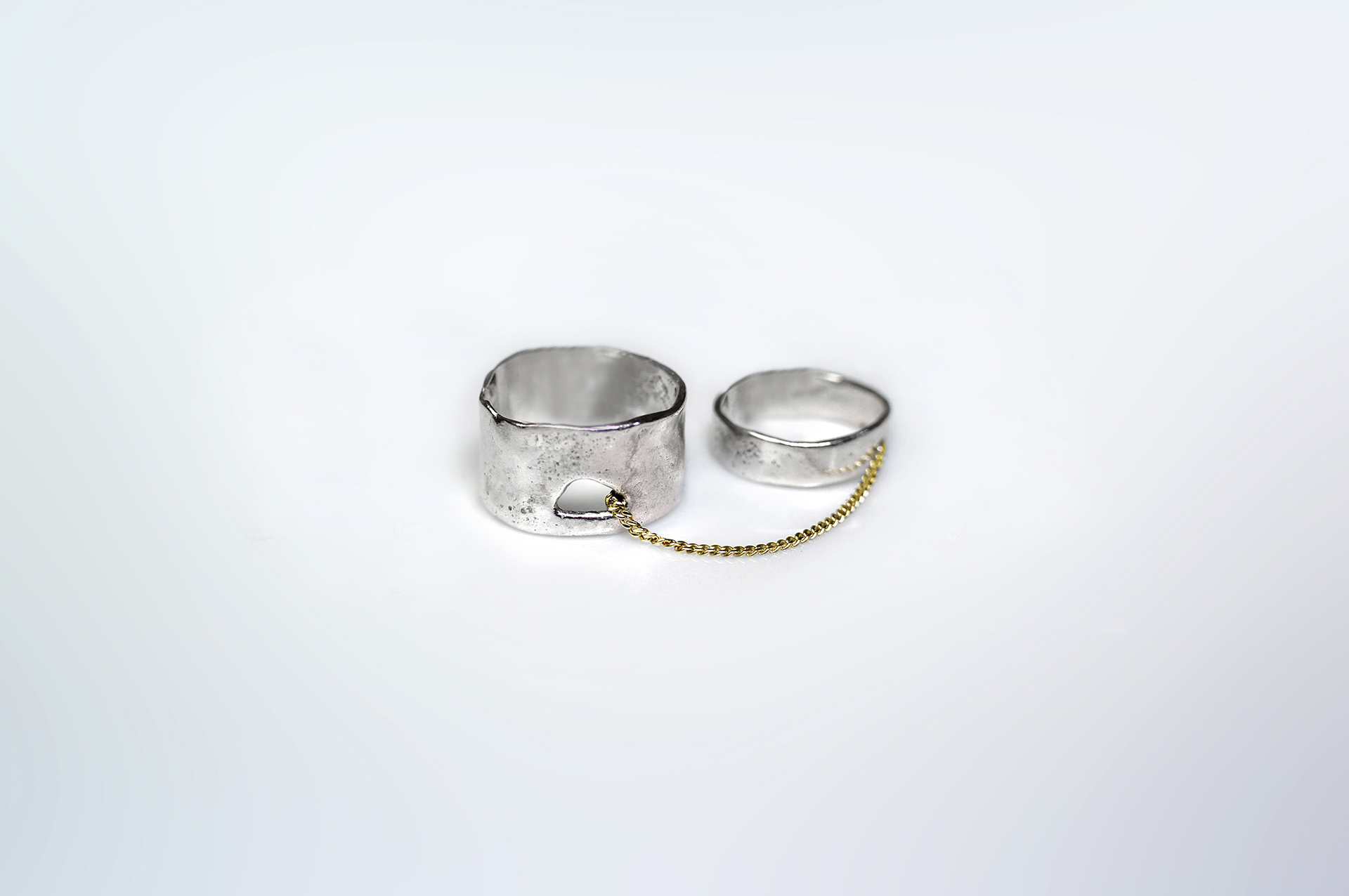 Kara ring composed of two sterling silver bands linked by a 18k gold thin curb chain