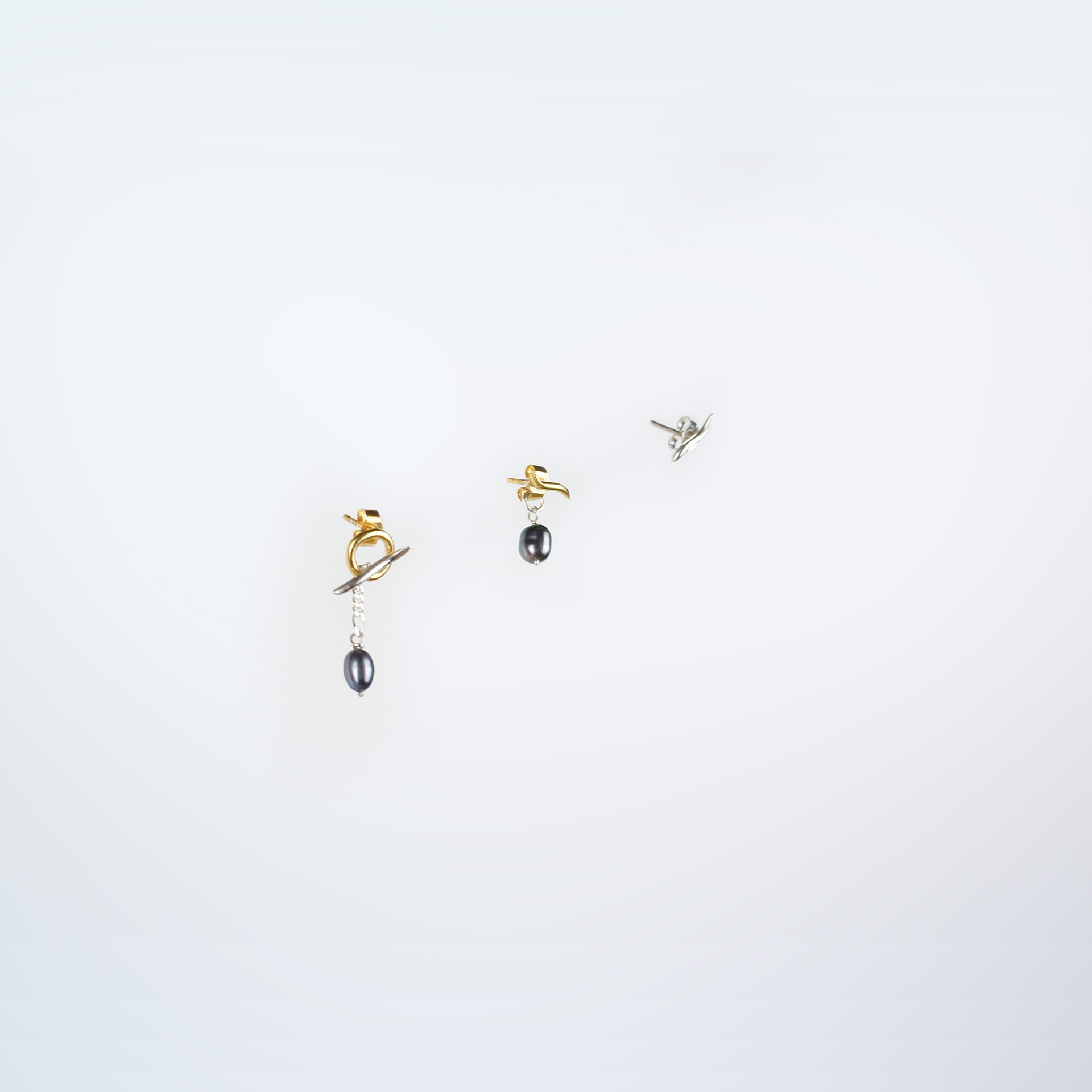 Mugura trio of stud earrings in silver and gold plated silver with dangling pearls.