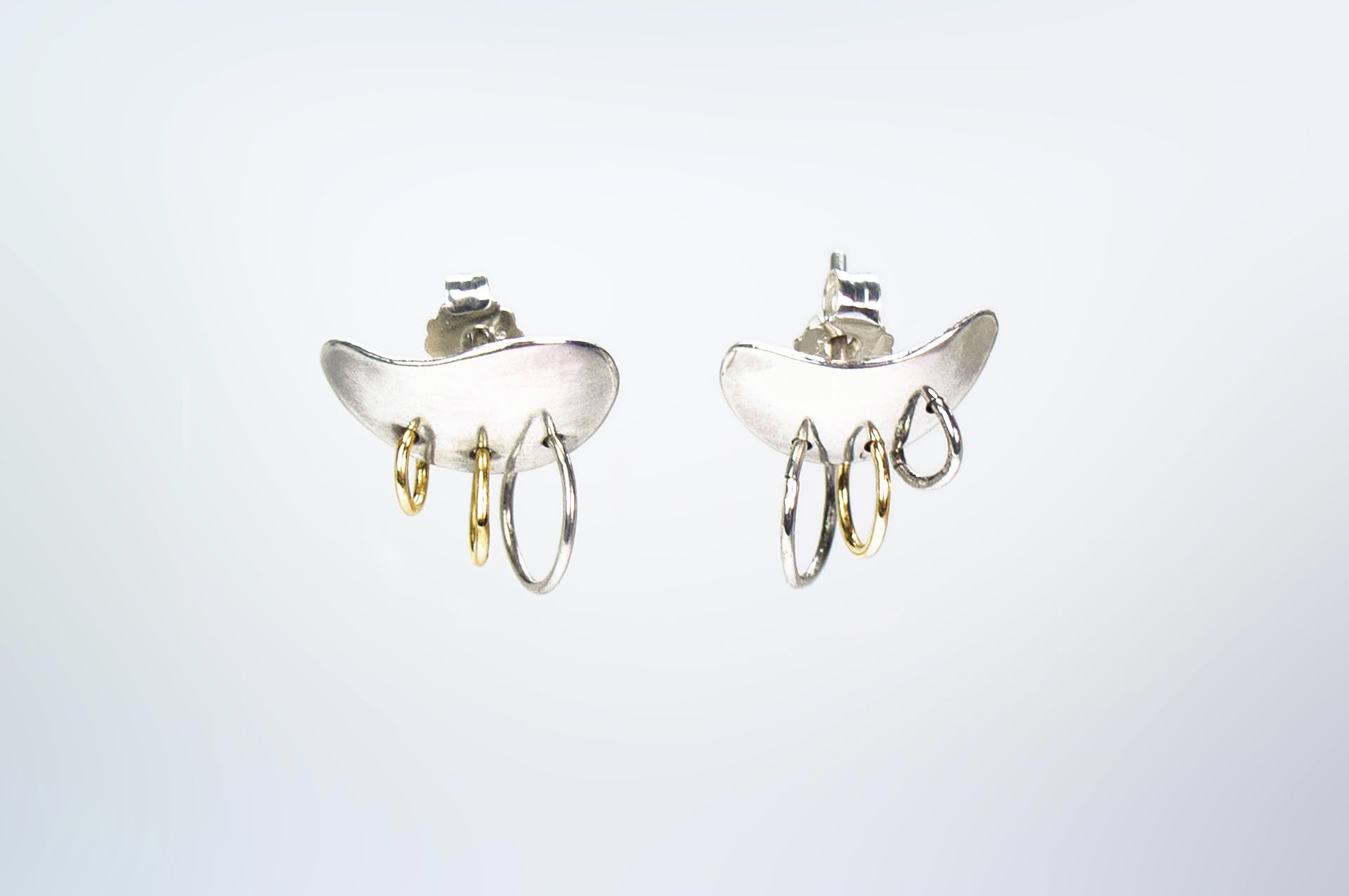 Piasu earrings in silver covering ear lobe with three hoops hanging on it