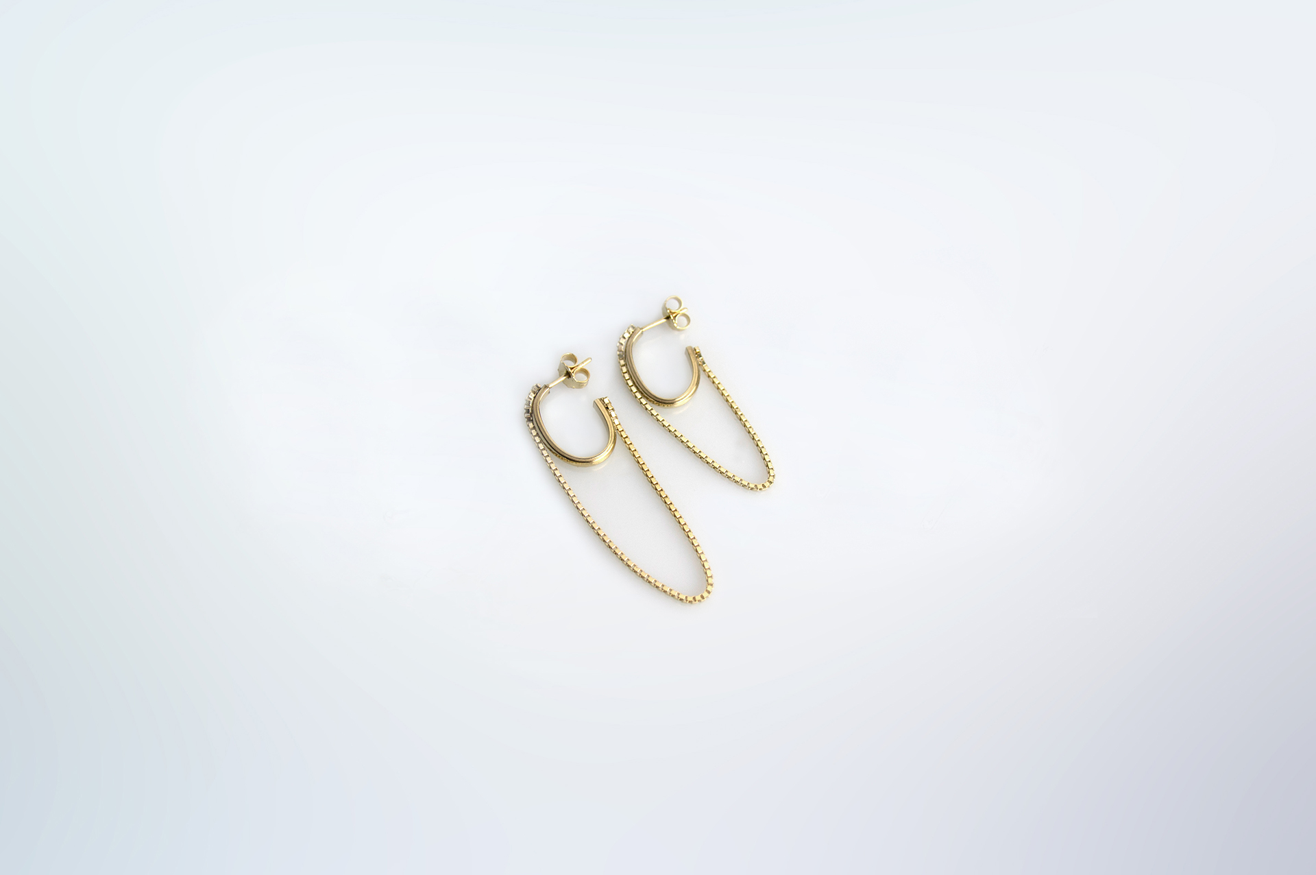 Tamanori oval gold plated hoops with dangling chains.