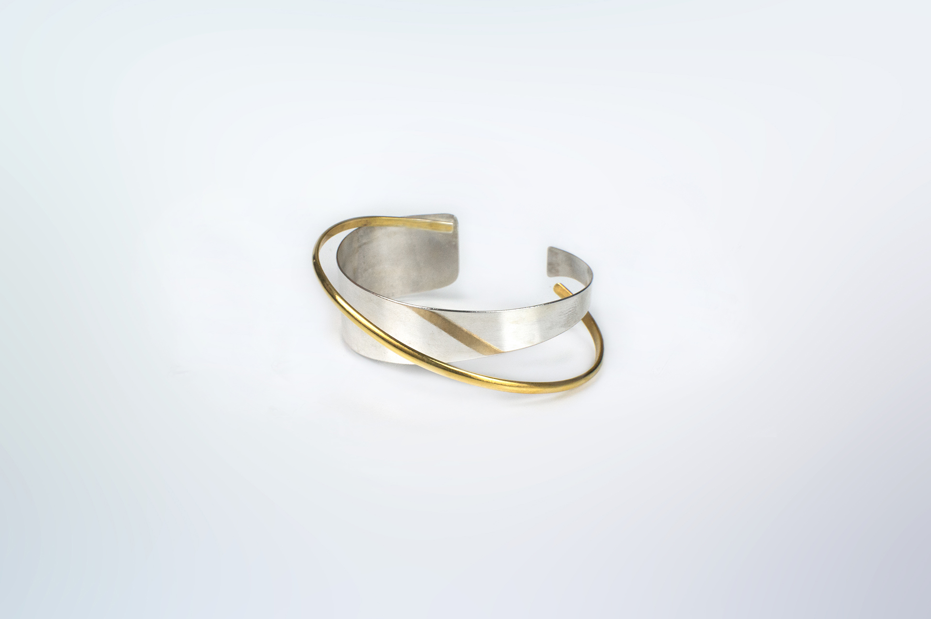 Hattari wide asymmetrical cuff crossed by gold plated thin band.