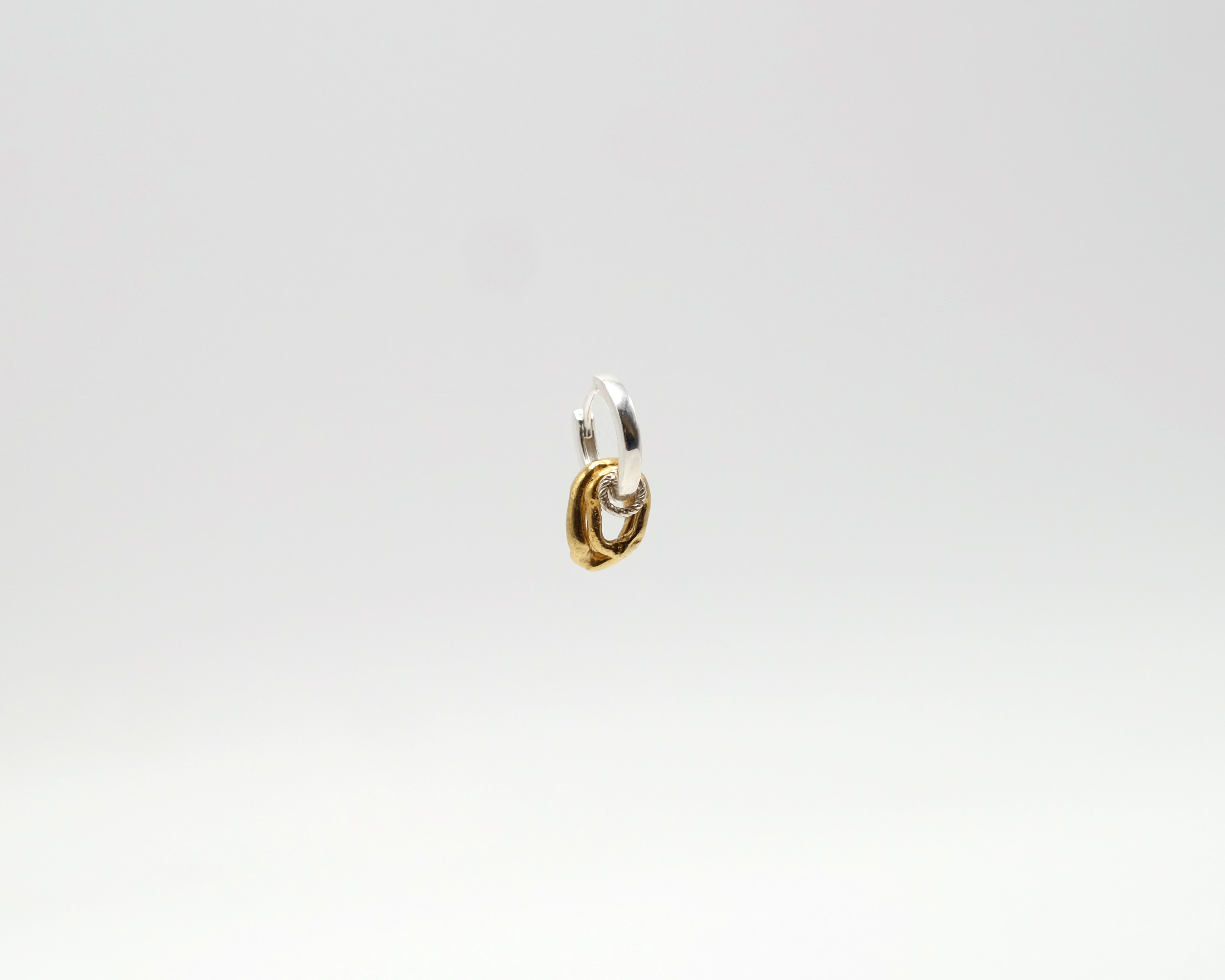 Fuyou solo hoop in sterling silver with gold plated rings hanging.