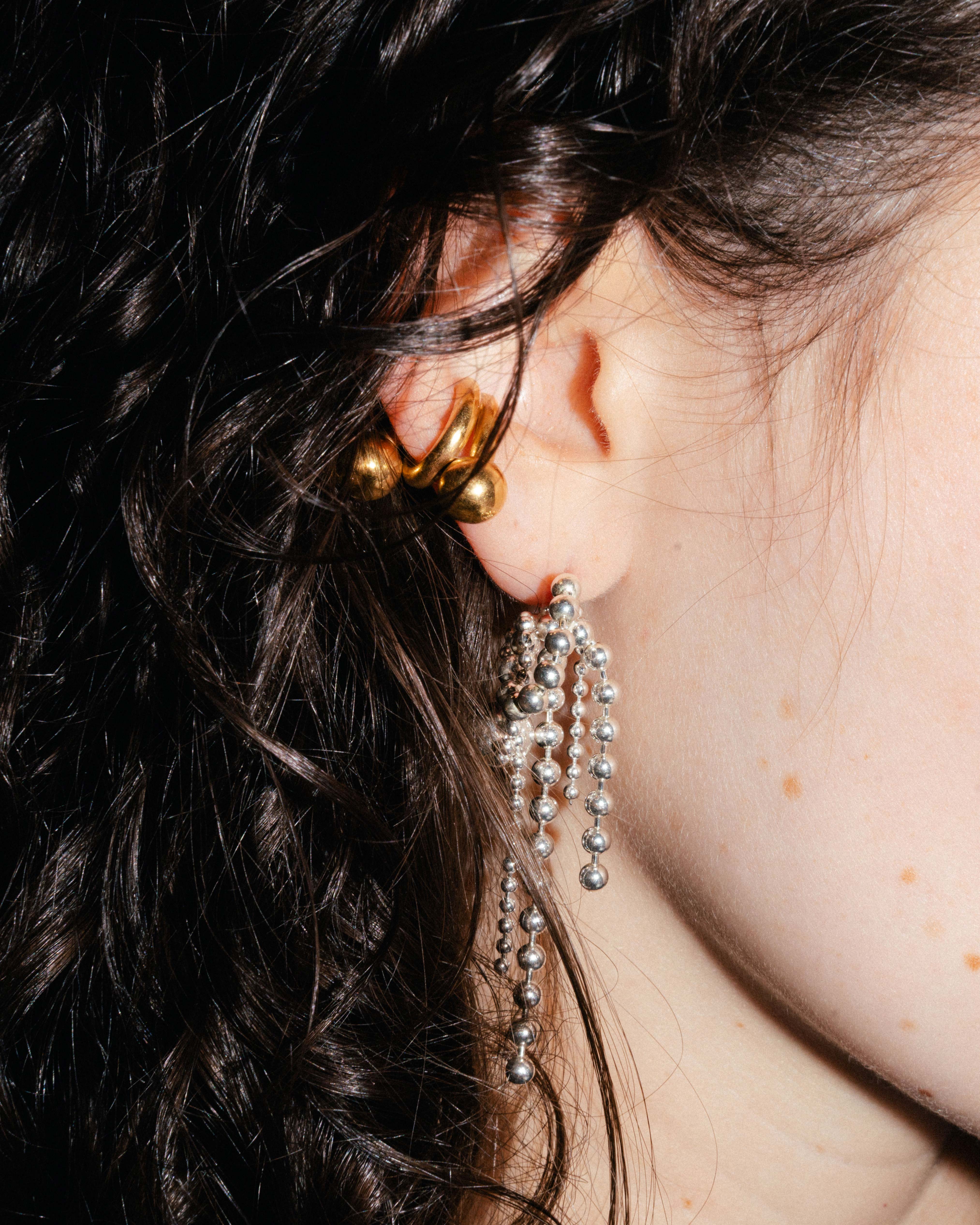 Piasu ear cuff in gold plated silver. A statement piece composed of thick wires and silver beads.