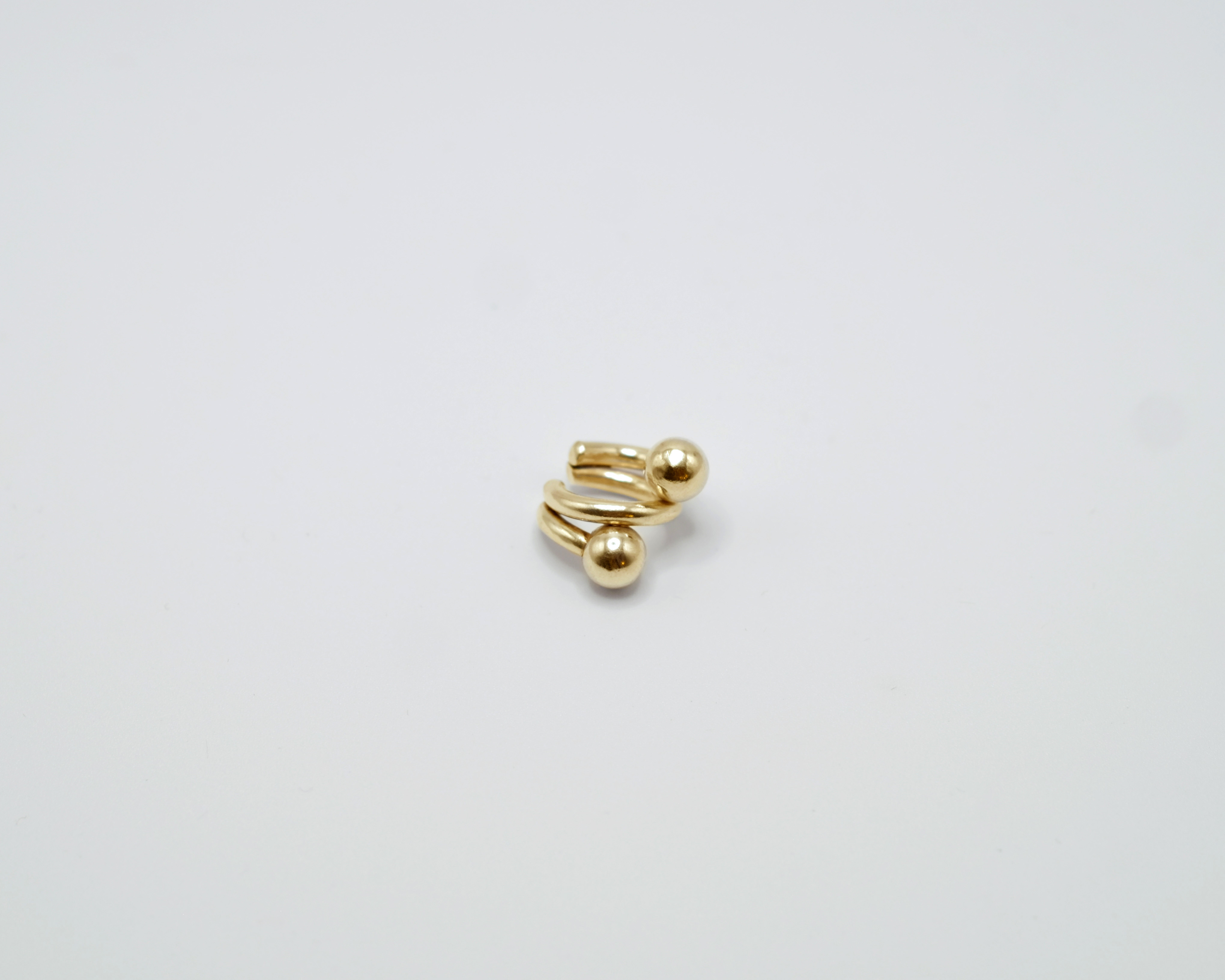 Piasu ear cuff in gold plated silver. A statement piece composed of thick wires and silver beads.